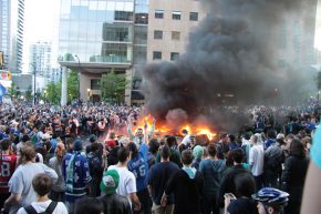 Rioters celebrating openly in front of a burning car in Vancouver